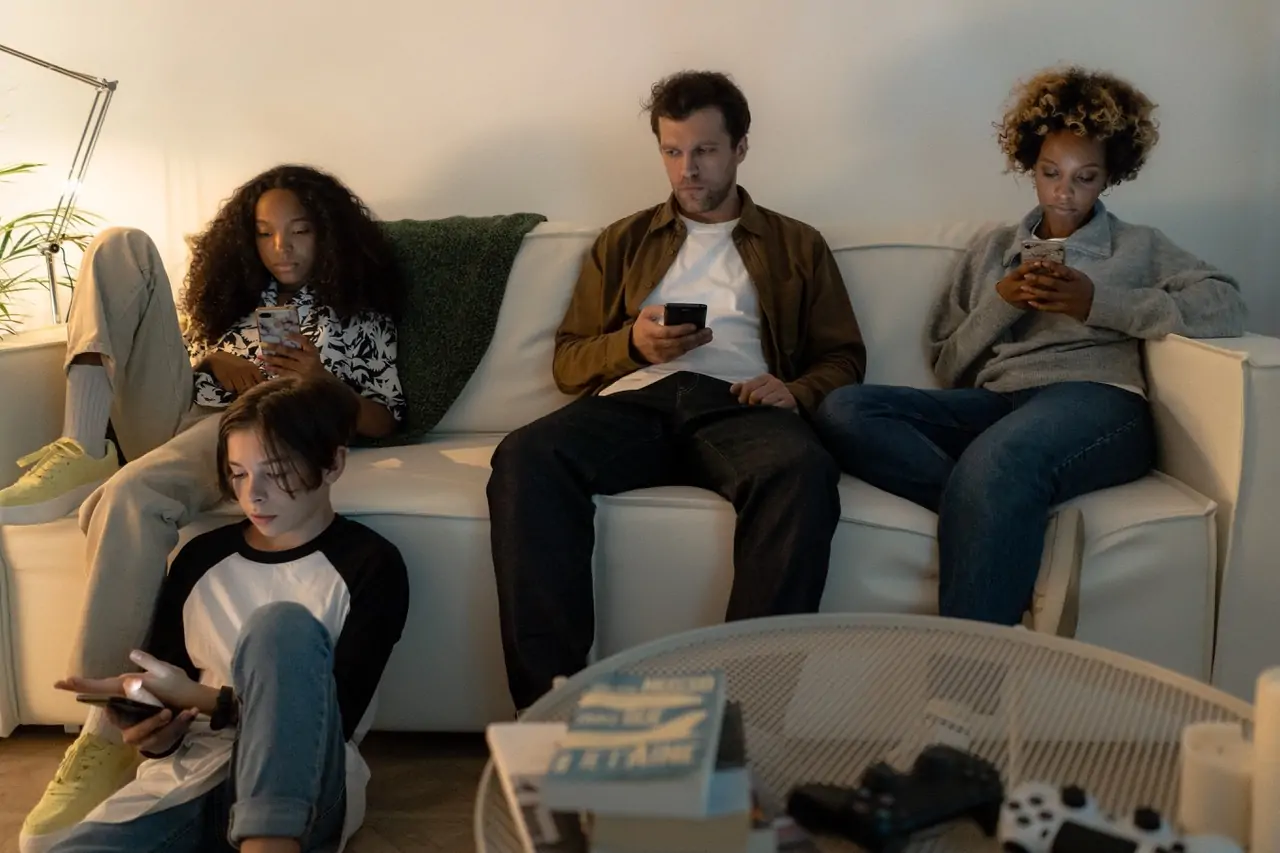 Family Sitting on a Sofa Looking at Their Cellphones