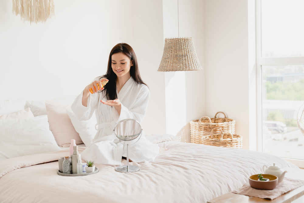 woman-on-the-bed-pouring-moisturizer-on-her-hand