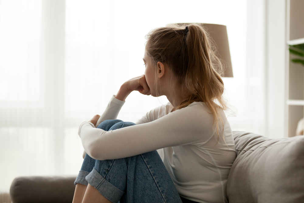 woman sitting on couch and looking at window
