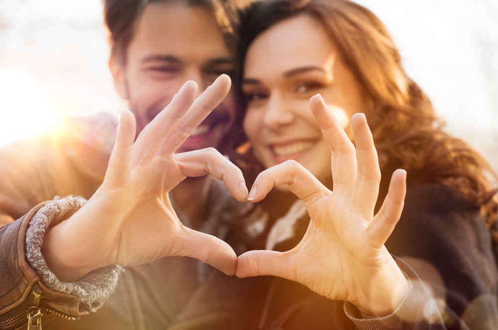 happy couple making heart shape with hands